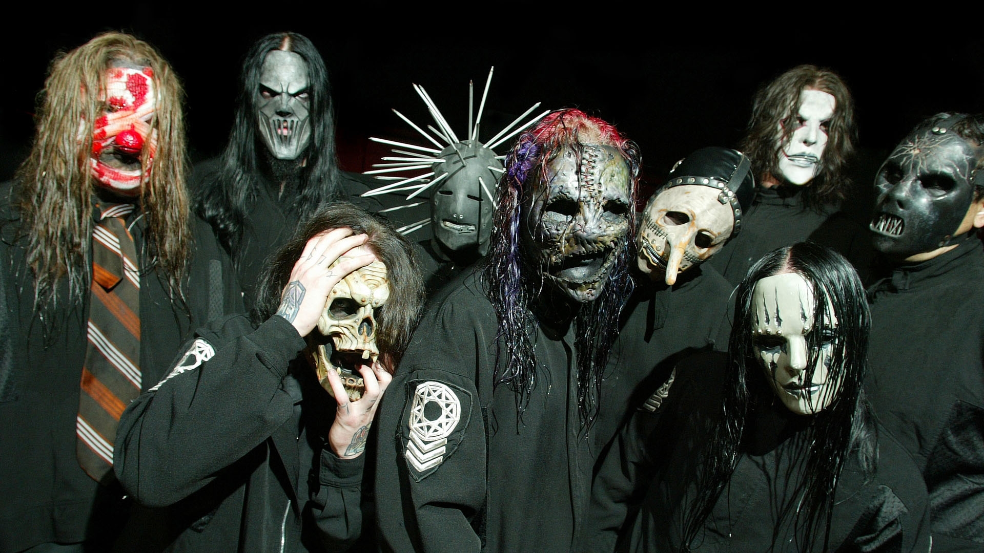 Integrantes do Slipknot em performance ao vivo, com máscaras e iluminação vermelha intensa